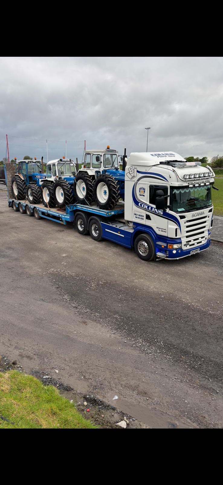 Blue and white truck transporting tractors